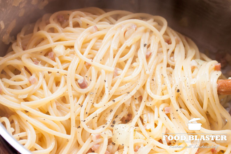 Spaghetti Carbonara mit Ei und Parmesan mischen